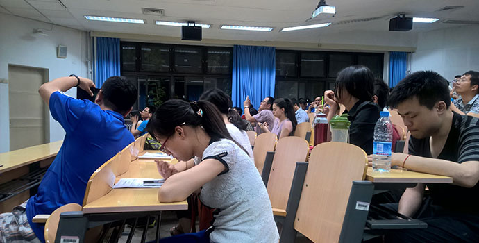 听众们不时用手机、纸笔记录下演讲精彩内容